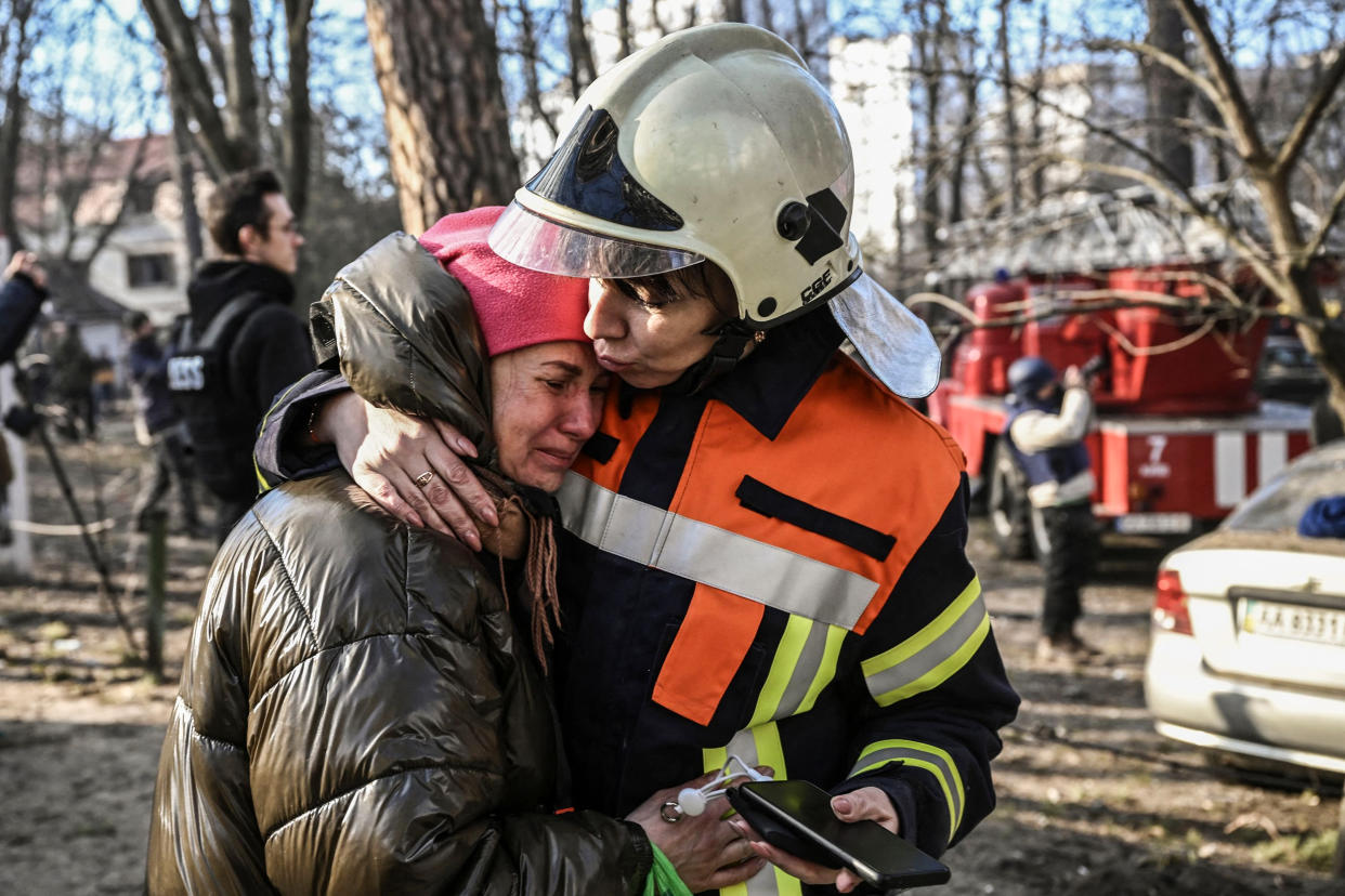 A rescue worker comforts an evacuated resident outside a burning apartment building in Kyiv on March 15, 2022. (Aris Messinis / AFP - Getty Images)