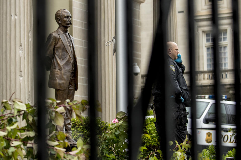 Bullet holes are visible on a column behind a statue of Cuban independence hero José Martí as a Secret Service officer investigates after police say a person with an assault rifle opened fire at the Cuban Embassy, Thursday, April 30, 2020, in Washington. Officers found the suspect with an assault rifle and took the person into custody without incident, police said. (AP Photo/Andrew Harnik)