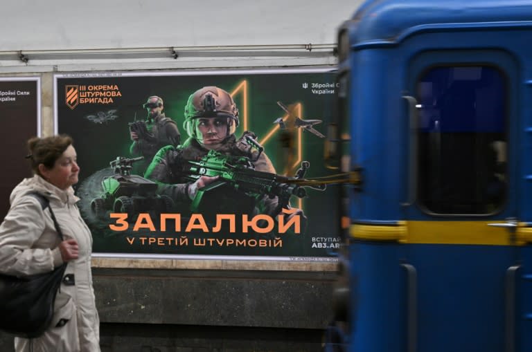 Una residente en Kiev pasa por delante de un cartel de reclutamiento de la Tercera Brigada de Asalto ucraniana mientras se refugia en el metro tras una alerta de ataque aéreo el 23 de abril de 2024 (Sergei Supinsky)