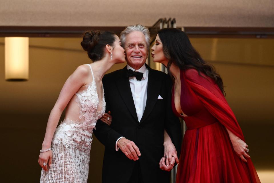 Carys Zeta Douglas and mother Catherine Zeta-Jones lean in to kiss Michael Douglas in a family moment on the Cannes red carpet.