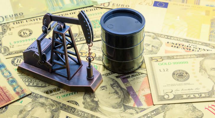 miniature oil barrel and oil well figures on top of stack of money