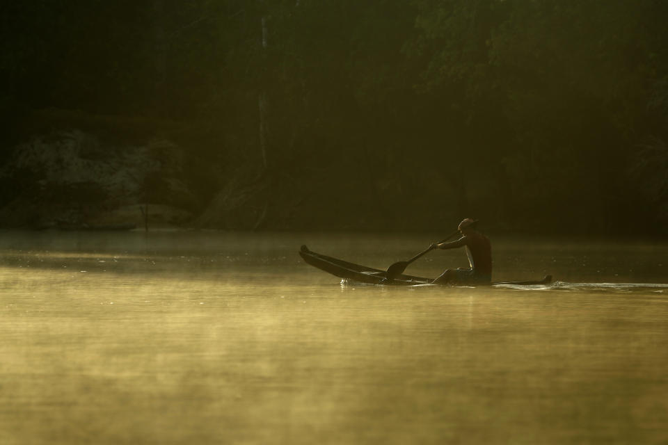 A Tenetehara Indigenous man paddles his canoe on the Gurupi River, in the Alto Rio Guama Indigenous Territory, where they have enforced six months of isolation during the COVID-19 pandemic, near the city of Paragominas, state of Para, northern region of Brazil, Monday, Sept. 7, 2020. The Indigenous group, also known as Tembe, held a festival this week to celebrate and give thanks that none of their members have fallen ill with COVID-19, after closing their area off in March. (AP Photo/Eraldo Peres)