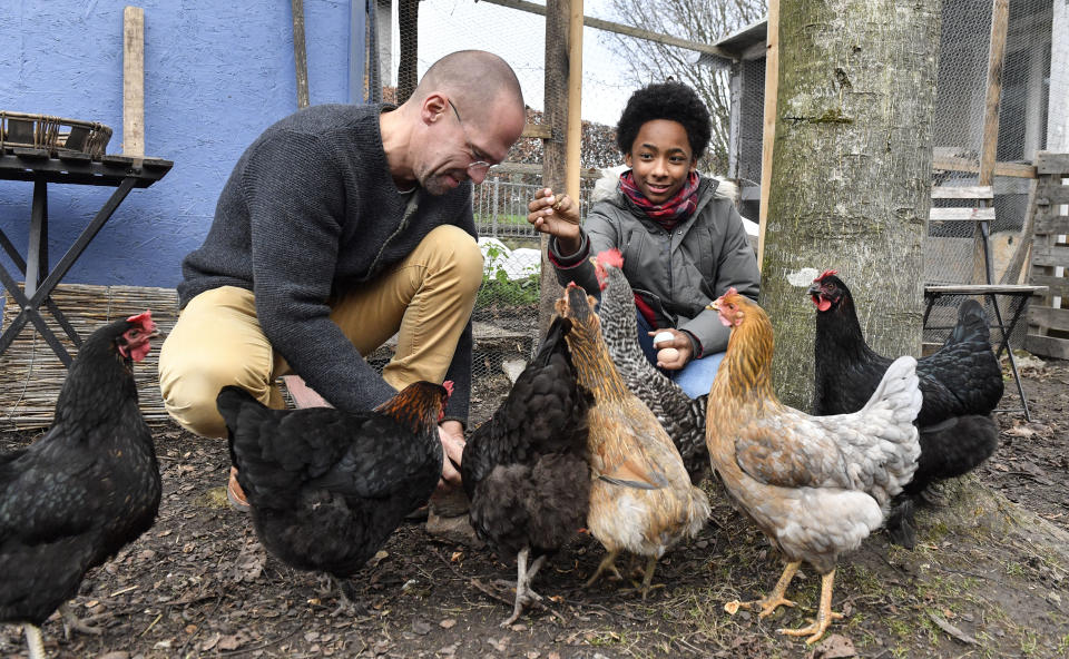 In this Dec. 7, 2018 photo Dirk Gratzel, left, and neighbor kid Elias feed their chicken in Stollberg, western Germany. Gratzel counts his carbon emissions. The software entrepreneur from Germany is among a growing number of people looking for ways to cut their personal greenhouse gas emissions from levels that scientists say are unsustainable if global warming is to be curbed. (AP Photo/Martin Meissner)