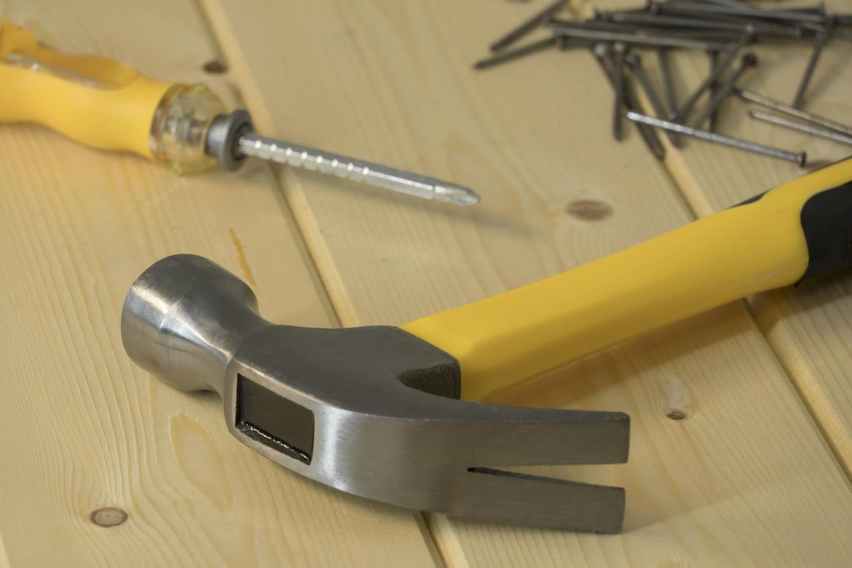 Assorted work tools on wood. Hand tools on a wooden background, hammer with nails and screwdriver. Home renovation, construction. Hand tools and equipment. An assortment of tools.