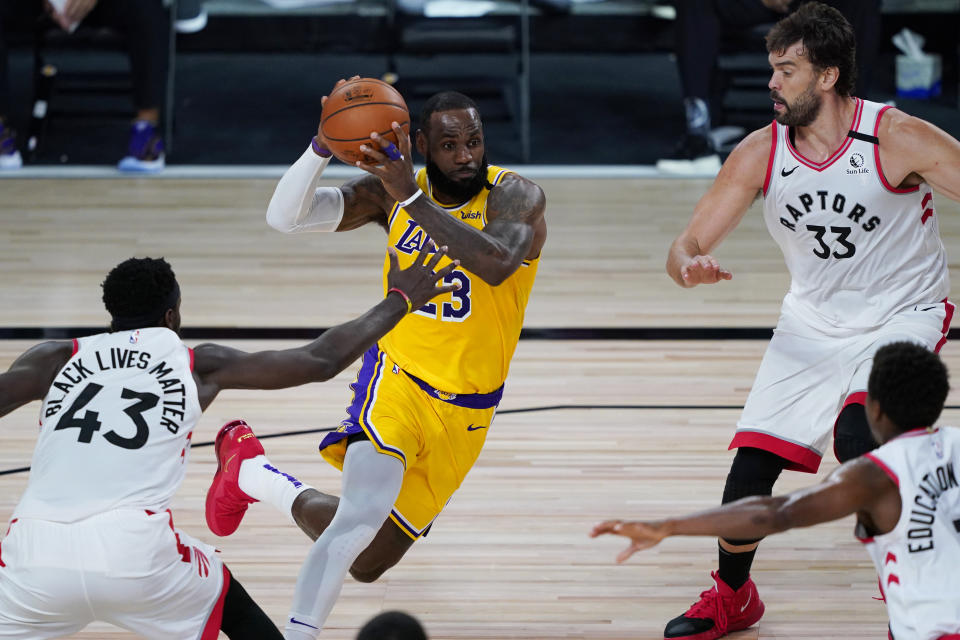 Los Angeles Lakers' LeBron James (23) drives around Toronto Raptors' Pascal Siakam (43) and Marc Gasol (33) during the first half of an NBA basketball game Saturday, Aug. 1, 2020, in Lake Buena Vista, Fla. (AP Photo/Ashley Landis, Pool)