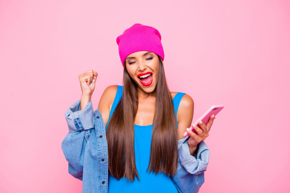 A young woman records herself singing a song on her smartphone.