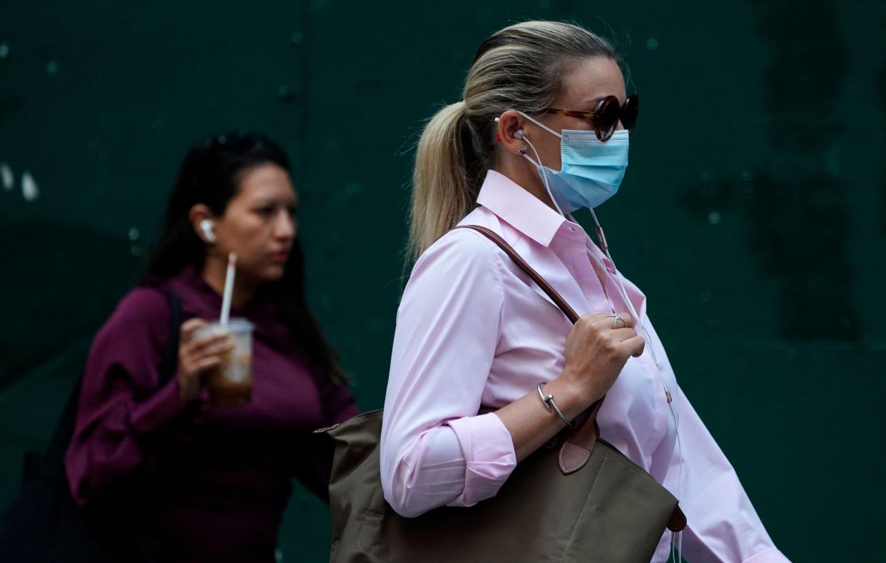 People walk through Times Square on 22 July  2021, as the Delta Covid surge is renewing calls for mask mandates in New York (AFP via Getty Images)