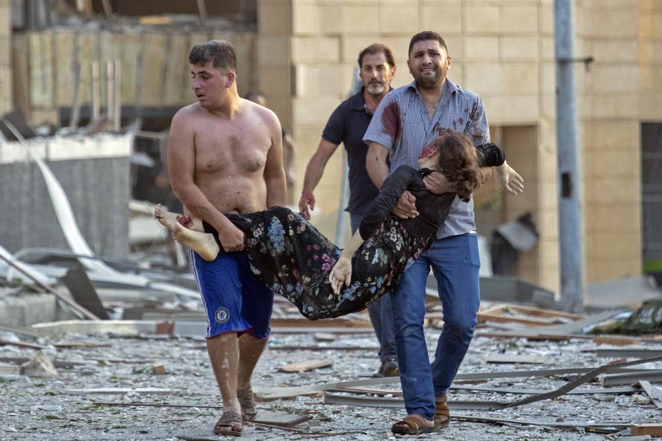 FILE - In this Aug. 4, 2020 file photo, Sedra Kinno, is carried by her brother Qoteiba, left, and her brother in law Fawaz in the aftermath of the massive explosion at the port in Beirut, Lebanon. The Kinno family from Syria's Aleppo region was devastated in the wake of the explosion -- Sedra, 15, died in the explosion, while her sister Hoda, 11, survived with a broken neck and other injuries. (AP Photo/Hassan Ammar, File)
