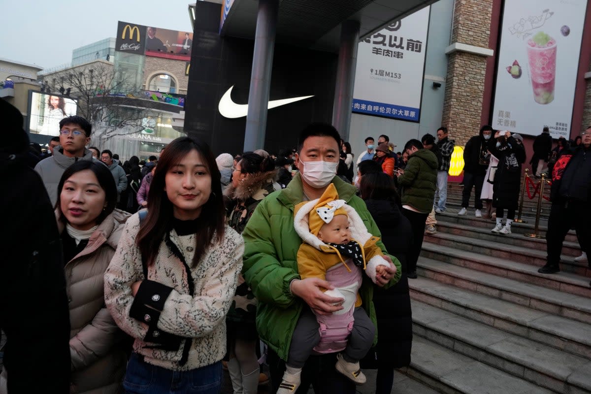 A man is pictured holding a baby at a Beijing shopping mall – but there are too few Chinese being born   (AP)
