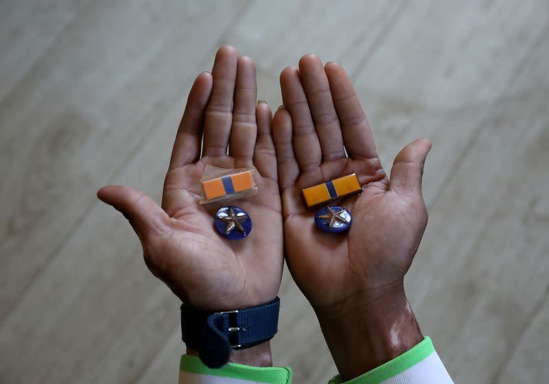 FILE PHOTO: A Myanmar national who said he was a policeman and recently fled to India shows his badges as he poses at an undisclosed location