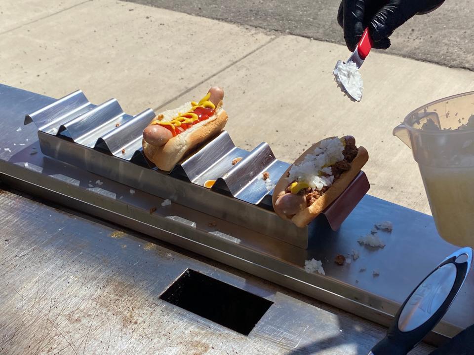 Toppings are added to coney dogs at the White Star Coneys stand in the parking lot of Bailey Park Supermarket in Pennfield Township in Thursday, June 30, 2022.