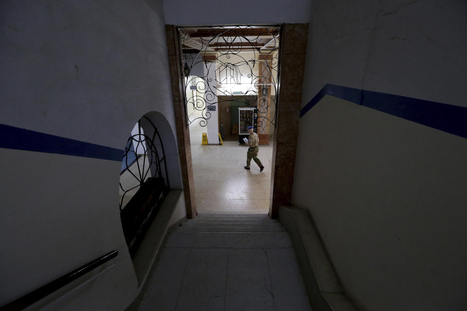 In this Friday, April 19, 2019, photo, a U.N peacekeeper crosses the lobby at the Ledra Palace hotel inside the U.N. buffer zone in the divided capital Nicosia, Cyprus. This grand hotel still manages to hold onto a flicker of its old majesty despite the mortal shell craters and bullet holes scarring its sandstone facade. Amid war in the summer of 1974 that cleaved Cyprus along ethnic lines, United Nations peacekeepers took over the Ledra Palace Hotel and instantly turned it into an emblem of the east Mediterranean island nation's division. (AP Photo/Petros Karadjias)