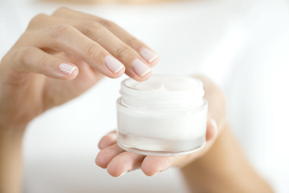 Female hand holding moisturizer in hand, vertical