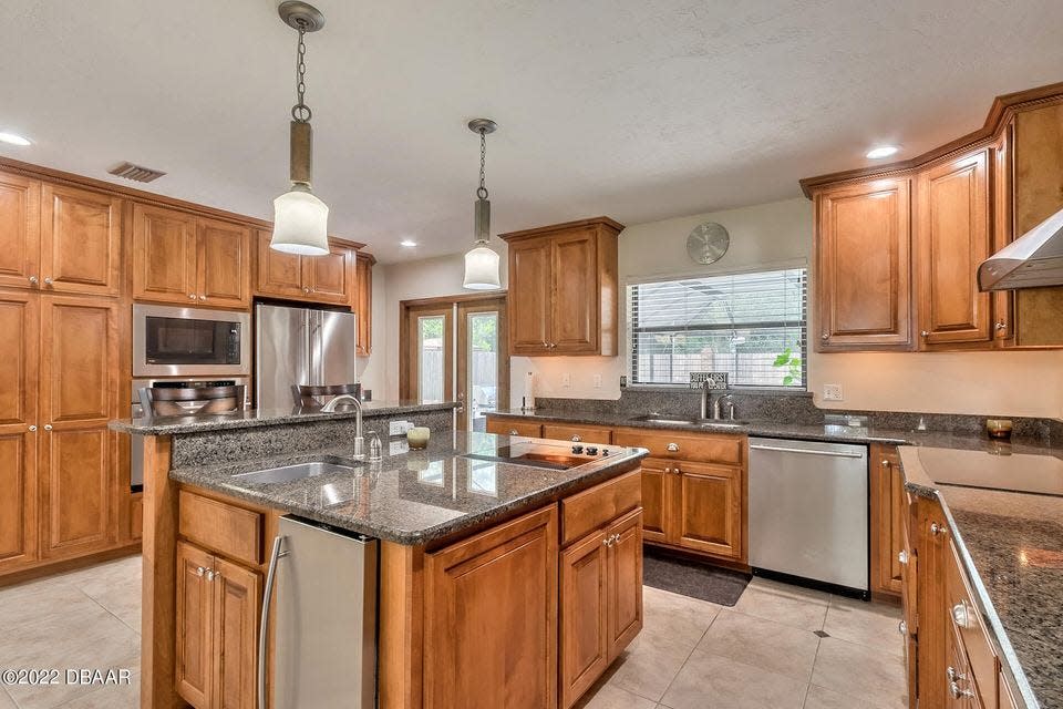 The masterfully designed chef's kitchen boasts granite countertops, custom wood cabinetry, a convection oven and an island with a JennAir griddle and prep sink.