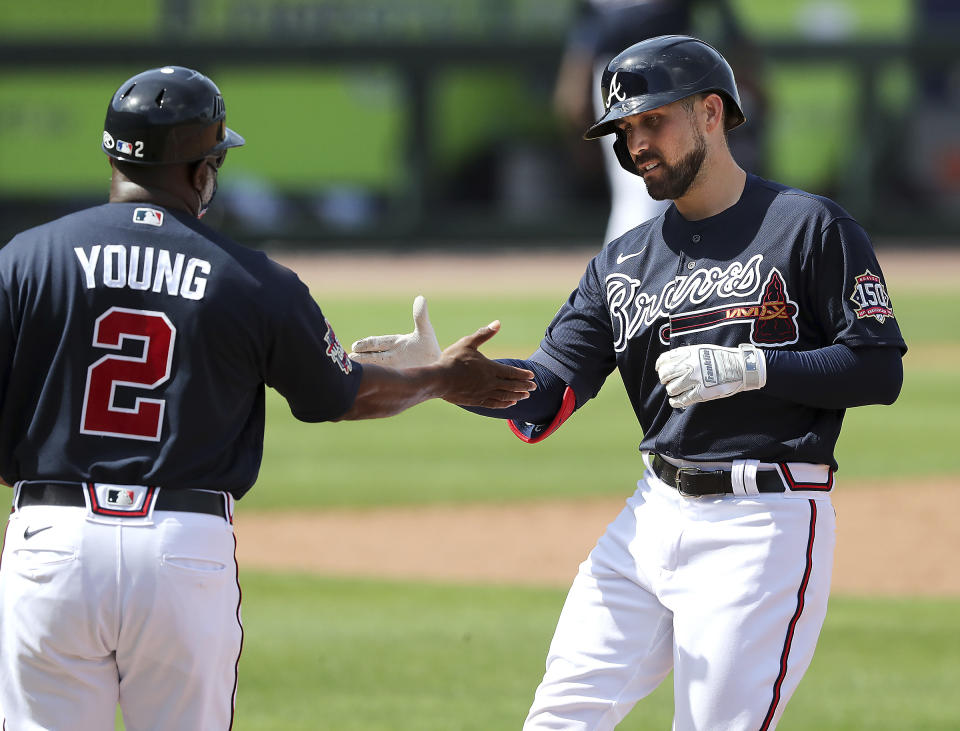 Atlanta Braves Ender Inciarte, right, gets five from first base coach Eric Young, left, after hitting a single against the Minnesota Twins during the third inning of an MLB spring training game Tuesday, March 2, 2021, in North Port, Fla. (Curtis Compton/Atlanta Journal-Constitution via AP)