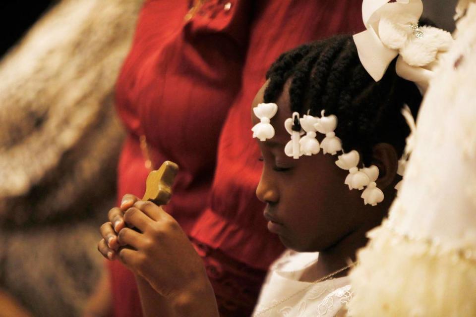 Eight-year-old Gregolia Desir watches as Archbishop Wenski celebrates the Liturgy of the Lord’s Passion on Good Friday.