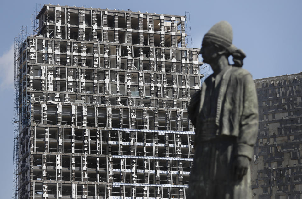 Una estatua que representa al expatriado libanés frente a un edificio dañado por una explosión en el puerto de Beirut, en esta fotografía del miércoles 5 de agosto de 2020. (Foto AP/Hussein Malla)