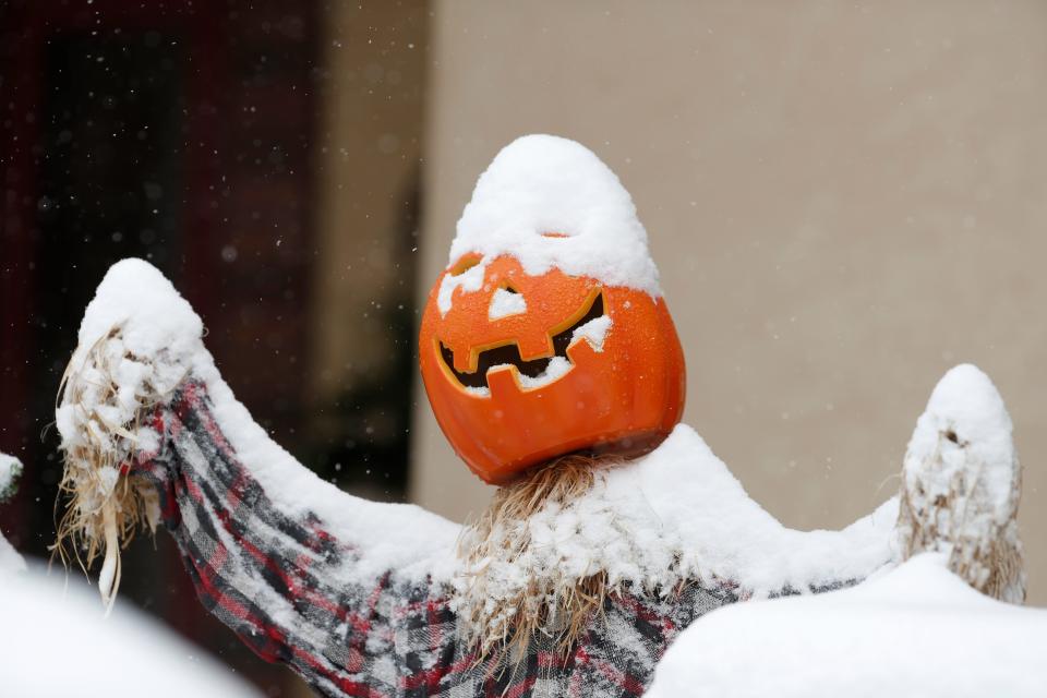 Snow covers a pumpkin used as part of a Halloween display outside a home as the season's first snow storm sweeps over the metropolitan area Thursday, Oct. 10, 2019, in Denver.