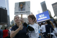 Rachel White, left, of Cherry Hill, N.J., and her aunt Dolores White, of Forest Hills, N.Y., hold aloft a sign memorializing Rachel's brother James Patrick White as friends and relatives of the victims of 9/11 gather for a ceremony marking the 10th anniversary of the attacks at the National September 11 Memorial at the World Trade Center site, Sunday, Sept. 11, 2011, in New York. (AP Photo/Jason DeCrow)