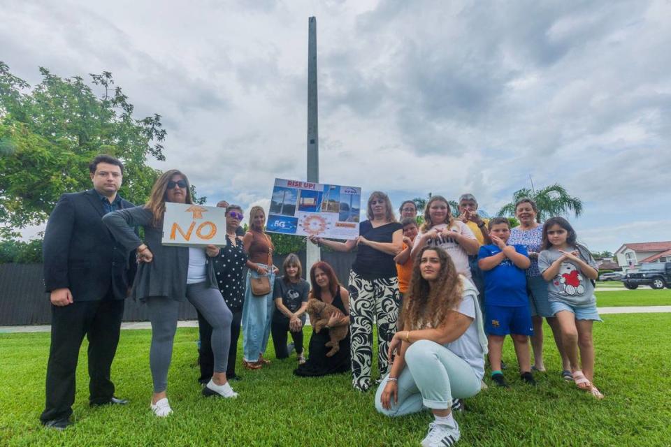 A group of residents concerned over 5G towers popping up in Kendall neighborhoods poses next to a pole next behind a house at 11495 SW 101 Terrace on Friday, July 5, 2024.