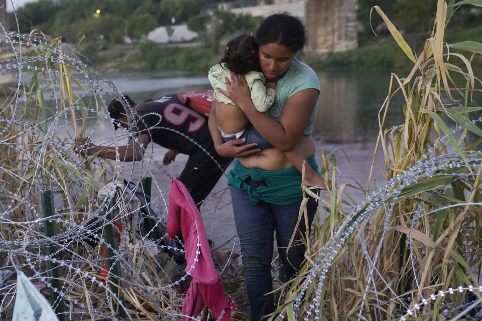 Migrants climb over concertina wire after they crossed the Rio Grande and entered the U.S. from Mexico, Saturday, Sept. 23, 2023, in Eagle Pass, Texas. (AP Photo/Eric Gay)