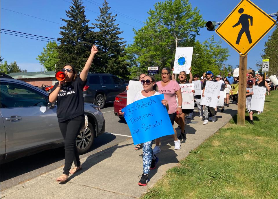 Giovanna Larios, left, holds a speaker in her hand and leads around 150 people to march from North Point Church to the North Kitsap School District office in the "Eliminate Racial Violence" protest on May 18, 2023.