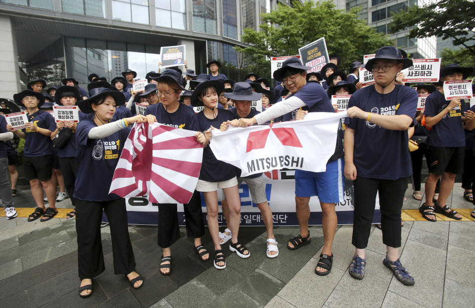 FILE - South Korean college students tear banners showing an image of a Japanese rising sun flag and the logo of Mitsubishi Corp. during a rally to denounce Japan's new trade restrictions on South Korea in front of the office of Mitsubishi Corp. in Seoul, South Korea, on Aug. 7, 2019. South Korean and Japanese leaders will meet in Tokyo on Thursday, March 16, 2023, beginning their first bilateral summit in more than a decade, and hoping to overcome resentments that date back more than 100 years. (AP Photo/Ahn Young-joon, File)