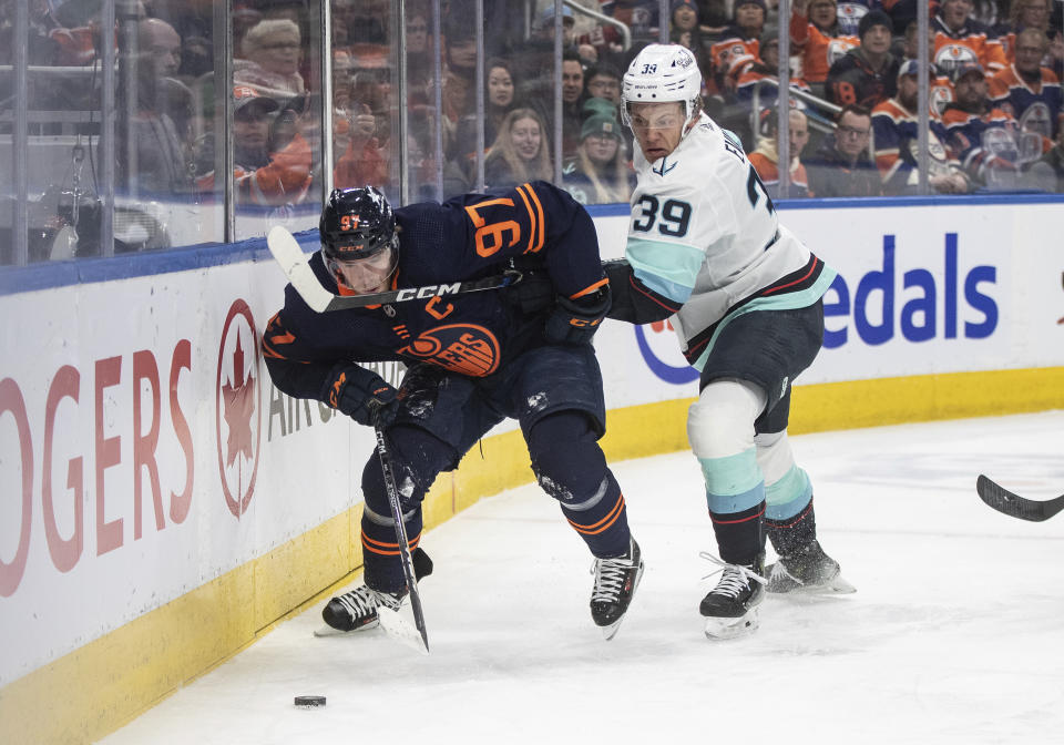 Seattle Kraken's Ryker Evans (39) and Edmonton Oilers' Connor McDavid (97) battle for the puck during second-period NHL hockey game action in Edmonton, Alberta, Thursday, Jan. 18, 2024. (Jason Franson/The Canadian Press via AP)