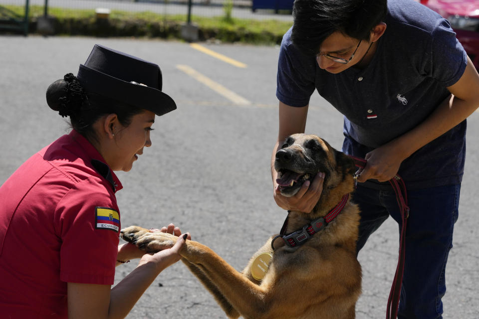 Una bombero se despide de Kratos, un perro que trabajaba con el departamento que se retiró, en Quito, Ecuador, el 20 de mayo de 2024. Los perros fueron adoptados por residentes en la capital. (AP Foto/Dolores Ochoa)