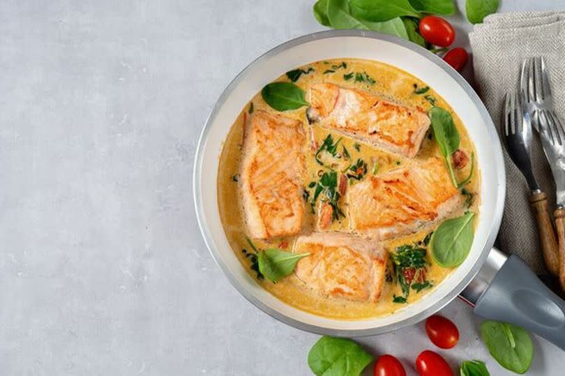 Delicious salmon steaks in cream sauce on light background