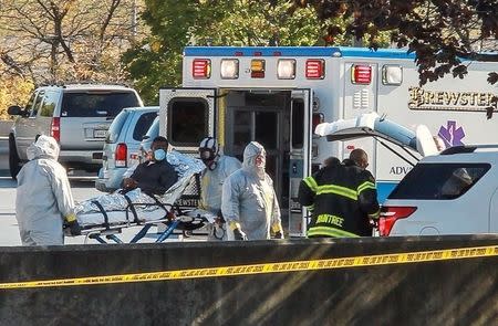 Ambulance workers wearing protective gear load a patient with possible Ebola symptons into the back of an ambulance at the Harvard Vanguard facility in Braintree, Massachusetts October 12, 2014 in this still image from video. REUTERS/Kevin Wiles Jr.