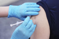 An employee of the beverage maker Suntory takes a Moderna COVID-19 vaccine shot at their office building as the company began its workplace vaccination Monday, June 21, 2021, in Tokyo. Thousands of Japanese companies began distributing COVID-19 vaccines to workers and their families Monday in an employer-led drive reaching more than 13 million people that aims to rev up the nation's slow vaccine rollout. (AP Photo/Eugene Hoshiko)