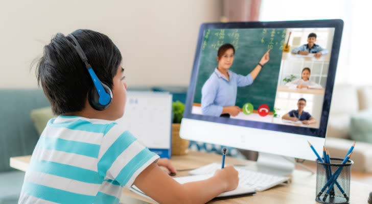 a child takes notes while attending an online class. represents education stocks. best-performing stocks