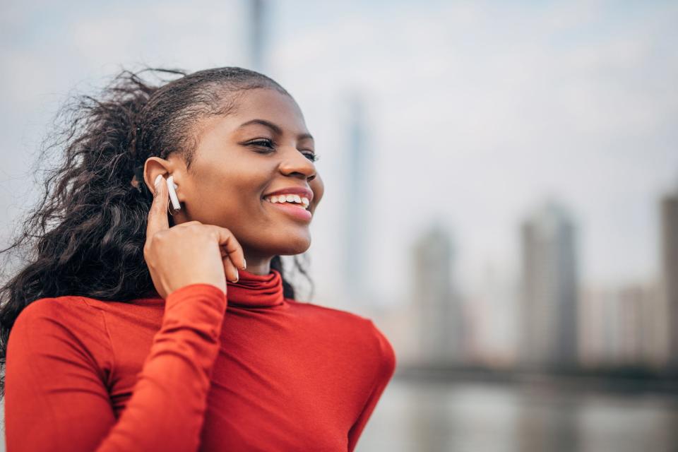 a smiling woman listens to air pods