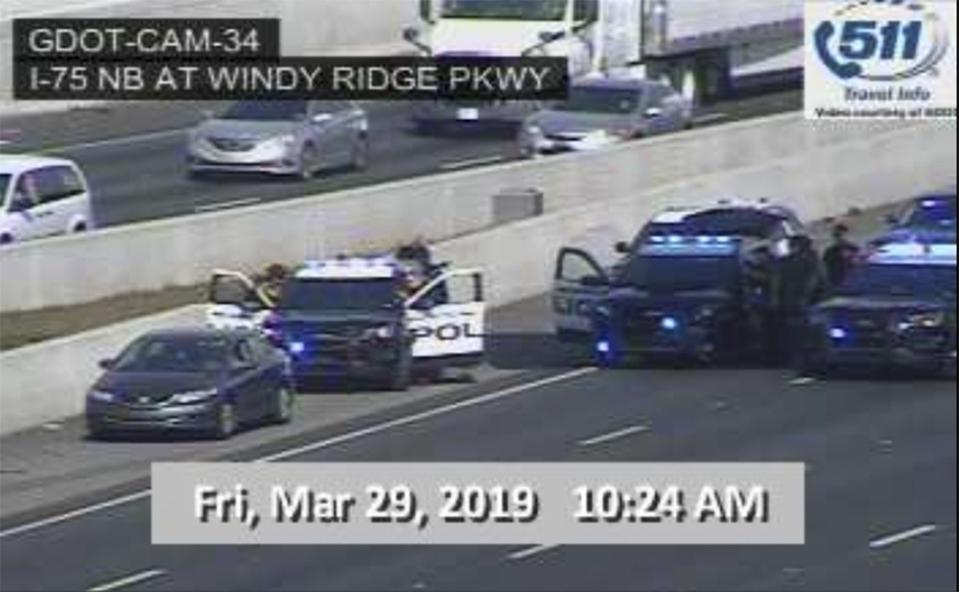 In this image made from video provided by the Georgia Department of Transportation, Marietta Police block southbound lanes on Interstate-75, near Marietta, Ga., North of Atlanta, Friday, March 29, 2019. Marietta police said in a brief statement that the southbound lanes of Interstate 75 were shut down Friday morning due to a motorist stopped on the freeway just northwest of Atlanta. Police described the motorist as a "non-compliant driver." (Georgia Department of Transportation via AP)