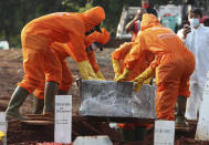 Workers in protective suits prepare a coffin containing the body of someone who presumably died of COVID-19 for burial at a cemetery in Jakarta, Indonesia Friday, June 12, 2020. As Indonesia’s virus death toll rises, the world’s most populous Muslim country finds itself at odds with protocols put in place by the government to handle the bodies of victims of the pandemic. This has led to increasing incidents of bodies being taken from hospitals, rejection of COVID-19 health and safety procedures, and what some experts say is a lack of communication from the government. (AP Photo/Achmad Ibrahim)