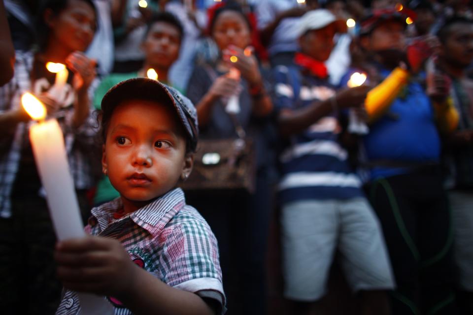 A boy holds a candle during a memorial service for the 16 Nepalese Sherpa guides killed in avalanche on Mount Everest in Katmandu, Nepal, Wednesday, April 30, 2014. The April 18 avalanche was the deadliest disaster on the world's highest mountain. (AP Photo/Niranjan Shrestha)