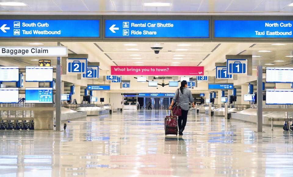 A lone traveler enters an empty baggage claim area in Terminal Four at Sky Harbor International Airport in Phoenix. Airlines are reducing flights due to the coronavirus COVID-19 outbreak.