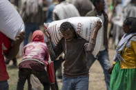 An Ethiopian man carries a sack of wheat on his shoulders to be distributed by the Relief Society of Tigray in the town of Agula, in the Tigray region of northern Ethiopia, on Saturday, May 8, 2021. In war-torn Tigray, more than 350,000 people already face famine, according to the U.N. and other humanitarian groups. It is not just that people are starving; it is that many are being starved, The Associated Press found. (AP Photo/Ben Curtis)