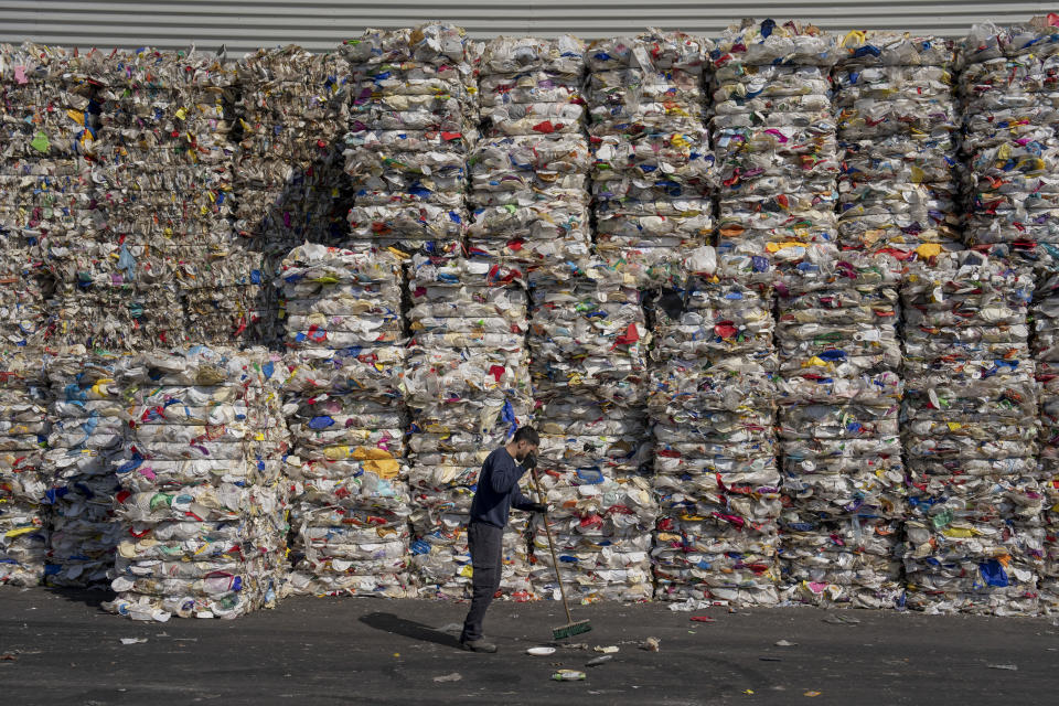 Un empleado de la planta de reciclaje GreenNet limpia el suelo junto a pilas de plásticos reciclables listos para exportar, en la zona industrial de Atarot, al norte de Jerusalén, el miércoles 25 de enero de 2023. Los judíos ultraortodoxos, que tienen familias numerosas y emplean una gran cantidad de cubiertos y vajilla desechable, dicen que el impuesto a los plásticos de un solo uso les señalaba de forma injusta. (AP Foto/Oded Balilty)