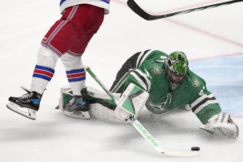 Dallas Stars goaltender Scott Wedgewood, right, dives to take control of the puck under pressure from New York Rangers right wing Kaapo Kakko, left, in the third period of an NHL hockey game in Dallas, Monday, Nov. 20, 2023. (AP Photo/Tony Gutierrez)