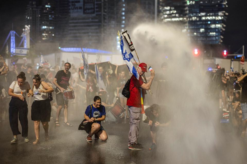 Demonstrators take cover from the Israeli police's water cannon, at a demonstration against Prime Minister Benjamin Netanyahu's government and a call for the release of hostages in Gaza, amid the Israel-Hamas conflict, in Tel Aviv