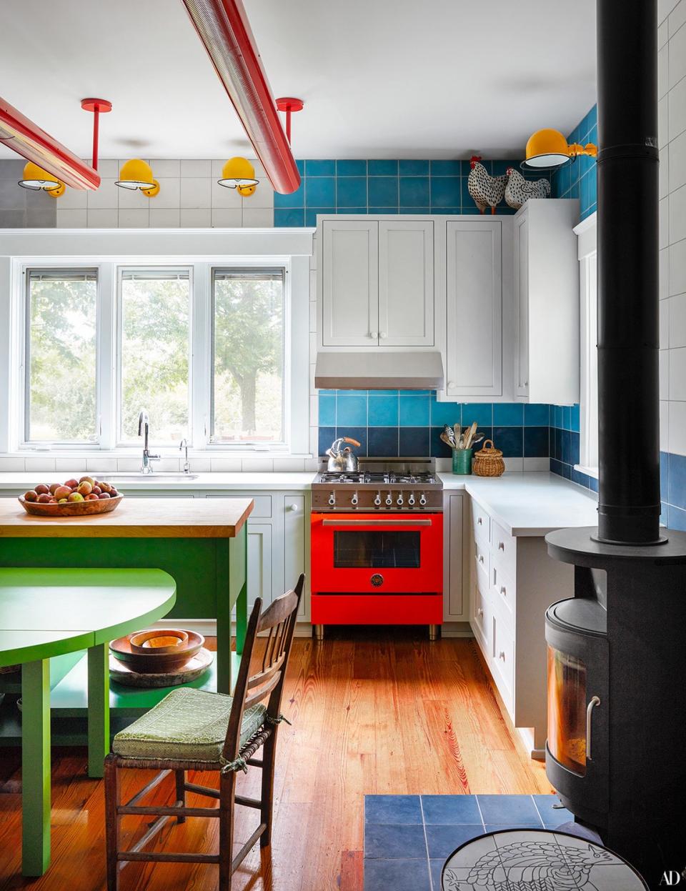 In the kitchen, custom cement tile by Mosaic House provides a serene backdrop for colorful accents. Bertazzoni range; Jieldé sconces; Rais wood-burning stove.