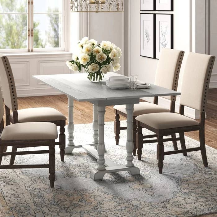 The table in white with both leaves open and with dining chairs around it