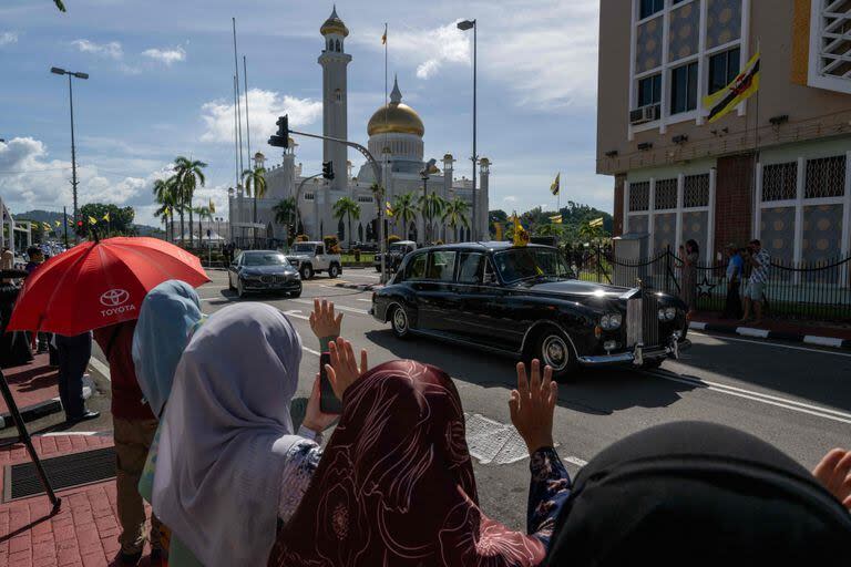 La gente saluda el paso del auto que traslada al sultán Hassanal Bolkiah en Bandar Seri Begawan, Brunéi. (Mohd RASFAN / AFP)