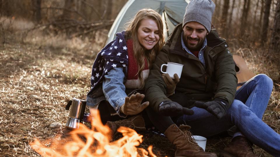 couple is sitting next to campfire