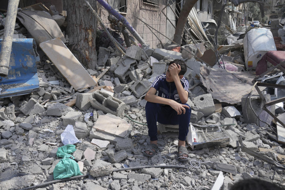 A Palestinian boy sits on the rubble of his building destroyed in an Israeli airstrike in Nuseirat camp in the central Gaza Strip on Monday, Oct. 16, 2023. (AP Photo/Hatem Moussa)