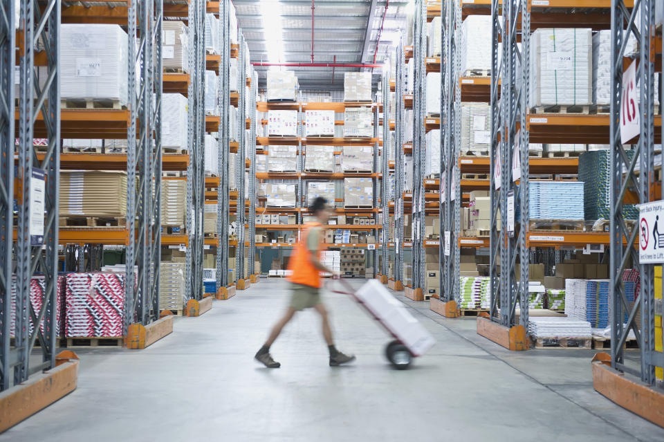 A worker pushes a trolley in a factory warehouse.