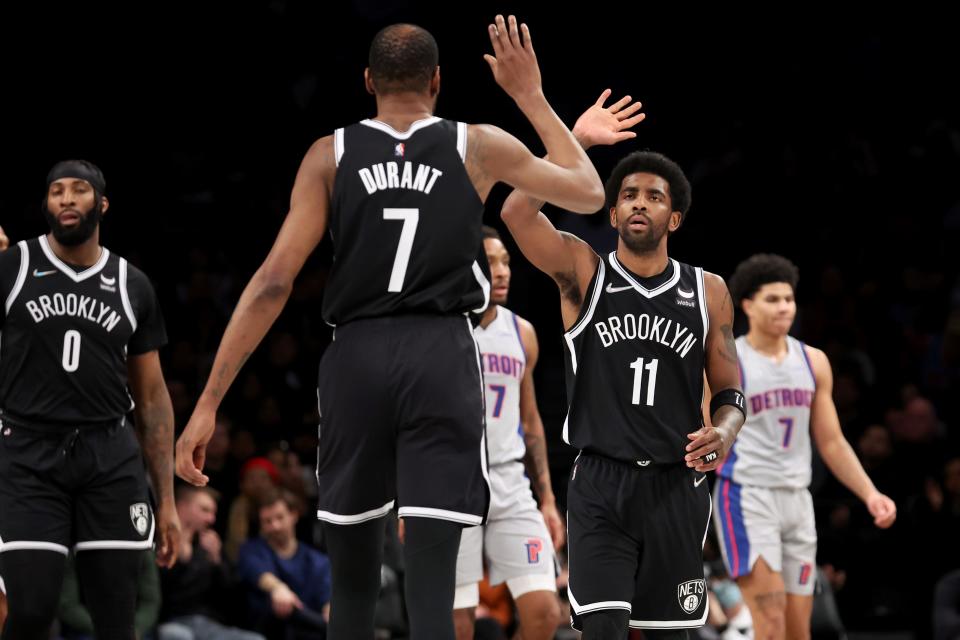 Nets guard Kyrie Irving high fives forward Kevin Durant during the second quarter on Tuesday, March 29, 2022, in Brooklyn, New York.