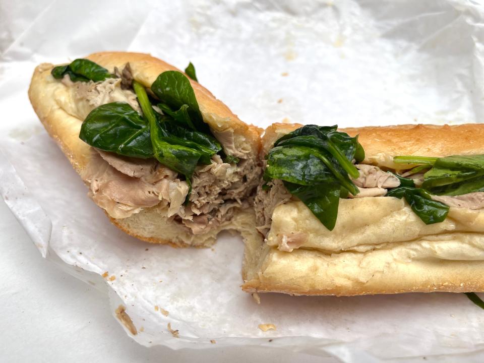 A roast pork sandwich with spinach and cheese on a wrapper